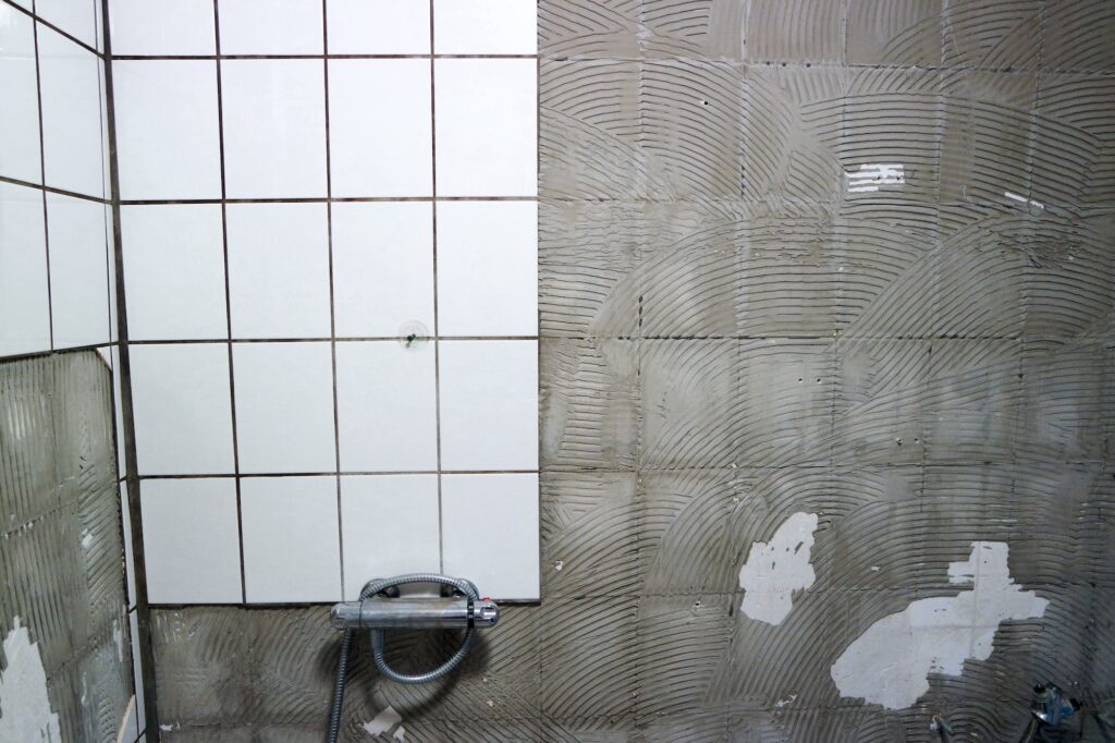 Bathroom renovation with halfway broken tiles on the wall.