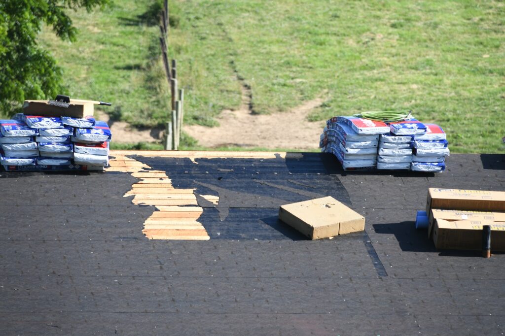 Roofers roofing company repairing a damaged roof with holes, insurance claim storm damage