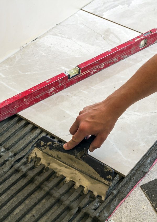 Ceramic tiles and tools for tiler. Worker hand installing floor tiles. Home improvement, renovation